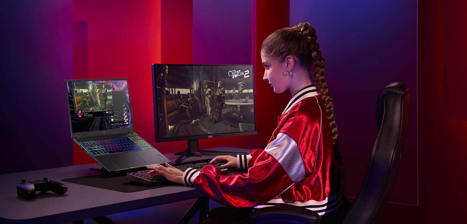 Mulher jovem de frente pra um computador, com uma segunda tela a direita.